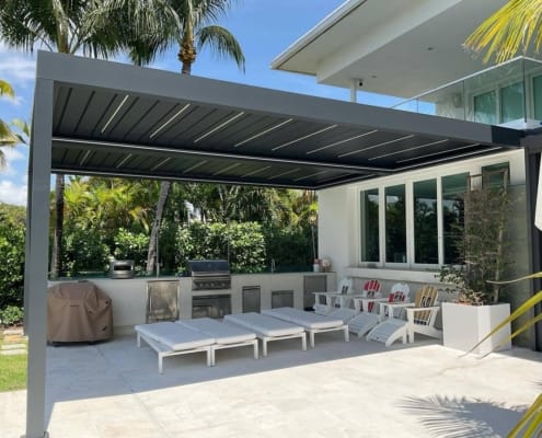 Heavy‑duty aluminum louvered pergola covering luxury outdoor kitchen at tropical waterfront villa patio