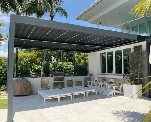 Heavy‑duty aluminum louvered pergola covering luxury outdoor kitchen at tropical waterfront villa patio