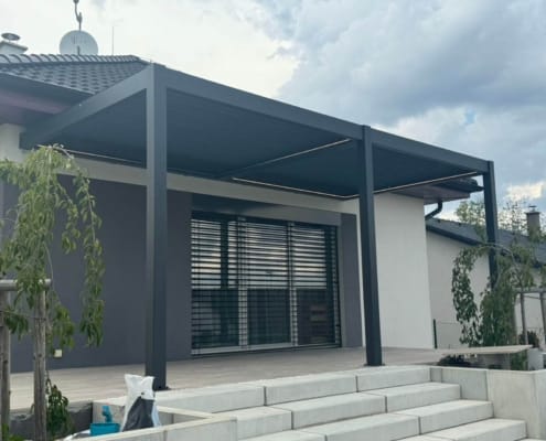 Motorized dark‑grey aluminum louvered pergola installed on modern family house outdoor terrace