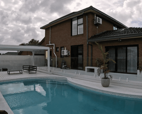 White powder‑coated aluminum louvered pergola beside swimming pool on residential wooden deck patio