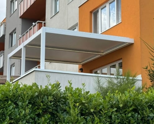 White motorized louvered aluminum pergola with integrated LED lights for apartment building rooftop terrace