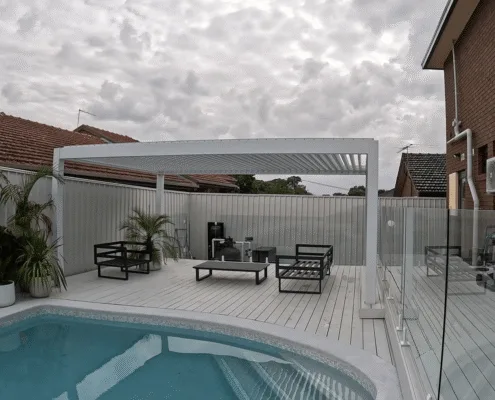 White motorized aluminum pergola louver roof for pool‑side outdoor lounge and relaxation area